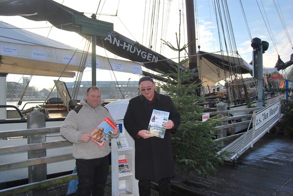 Schipper en reder Herman van Linschoten en Meinhard Siemens (v.l.n.r.) presenteren Friesland Holland bij de Jan Huygen op de kerstmarkt in Leer.