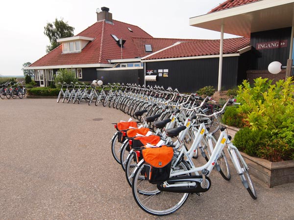 De eerste serie Fryslân Fietsen voor de deur van hotel Galamadammen in Koudum. De voorste vier, met oranje fietstassen, zijn voor gasten van Friesland Holland Travel die de Elfstedentocht fietsen.