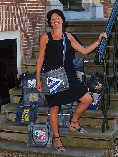 Jeannette Roeles heeft een hechte band met haar man en kinderen, maar ook met een fietsband. Hier draagt ze een geheel van oude fietsbanden gemaakte tas met een fietsvlaggetje van Friesland Holland Travel Service.
