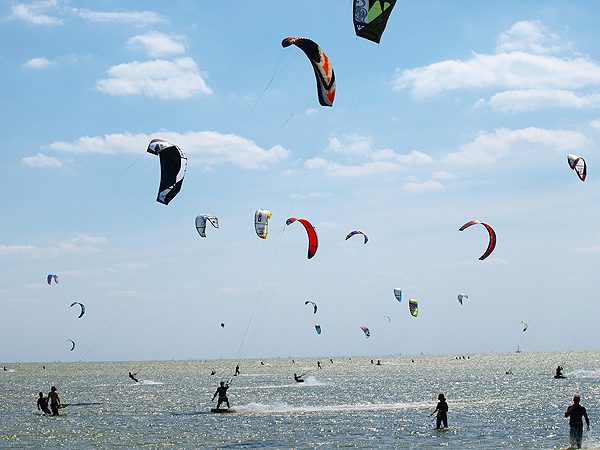 Schermen van kitesurfers vullen de weiden en de hemel bij Mirns.