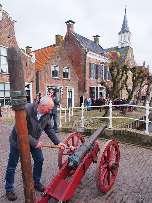 “It giet oan”. Henk Kroes, de oud-voorzitter van de Koninklijke Vereniging De Friesche Elf Steden, loste het kanonschot ter gelegenheid van de onthulling van ‘Pietsje en Evert van Hemert’s expositie in het stadhuis op de achtergrond.