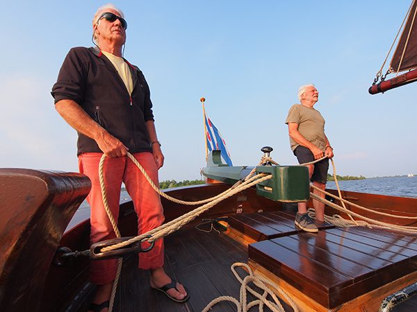 Vrijwillig schipper Sybren van der Meer, met zonnebril, stuurt de palingaak met toeristen over de Hegemer Mar terwijl hij verhaalt over het rijke palingverleden van Heeg, het Volendam van Friesland. 