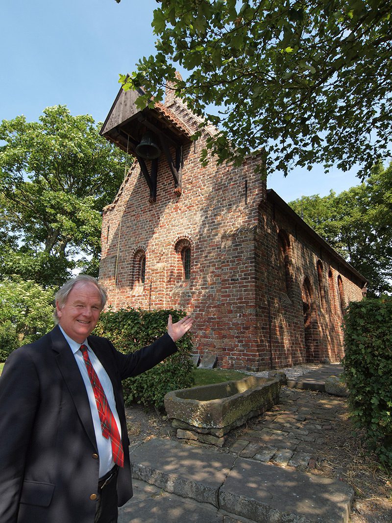 Wil van den Berg is burgemeester van de gemeente Ferwerderadiel, een regio met een bewoningsgeschiedenis van meer dan 5.000 jaar! Het kerkje van Jannum waar hij voor staat, is omstreeks 1150 gesticht. Het was vroeger een uithof van het niet meer bestaande klooster Klaarkamp (1165-1580) ten westen van Dokkum. Het Romaans aandoende Godshuisje staat op een terp, waarvan het grootste deel tot onder het maaiveld werd afgegraven. Er staan ook nog een paar gerestaureerde 19e eeuwse arbeidershuisjes. De kerk van Jannum was van 1580 tot 1938 een Hervormde kerk. Het fungeert nu als een soort museum van een bijzondere collectie sarcofagen (stenen grafkisten) uit de 11e en 12e eeuw. Buiten, aan de muur, hangt een kleine klokkenstoel. Het bouwwerk overleefde de reformatie, maar het werd wel leeggehaald. Het altaar werd in de deuropening begraven. In 1938 kwam een einde aan de functie van gebedshuis omdat de kerkgemeenschap nog maar één belijdend lid telde.