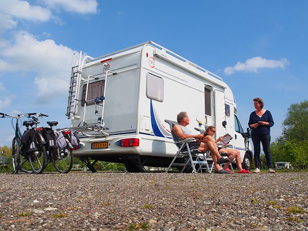 Jittie Mozes in gesprek met gasten. Camperliefhebbers fietsen graag in de Friese Wouden. 