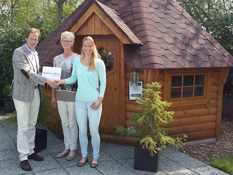 Betty en Hellen Bunt, mede-eigenaren sauna Het Friese Woud, ontvangen het muurschild Sauna en Wellness Nederland (SWNL) uit handen van Willem Kraanen, manager Sauna en Wellness Nederland.