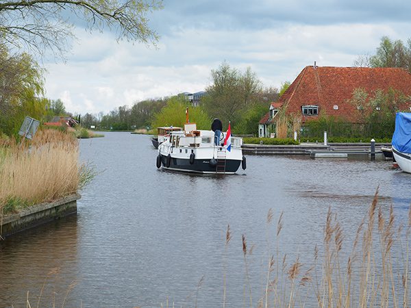 Niet te geloven: platteland midden in de stad. Een Multivlet van Yachtcharter Leeuwarden heeft net de charterbasis verlaten, varend op de Nauwe Greons.