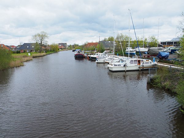 Niet te geloven: platteland midden in de stad. Een Multivlet van Yachtcharter Leeuwarden heeft net de charterbasis verlaten, varend op de Nauwe Greons.