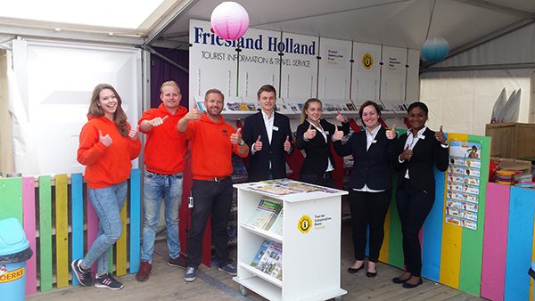 Roberto Schoenmaker van toeristisch informatiecentrum TIP Fryslân in Sneek (bovenste foto, derde van rechts) kreeg van de organisatie van het Zandsculpturenfestival Friesland in Sneek toestemming voor het inrichten van een infocenter (onderste foto). Hij vroeg en kreeg van het bureau voor toerisme Friesland Holland kosteloos een stand met alle gidsen en kaarten. Het infocenter staat de hele zomer in de ontvangsttent met horecavoorzieningen.