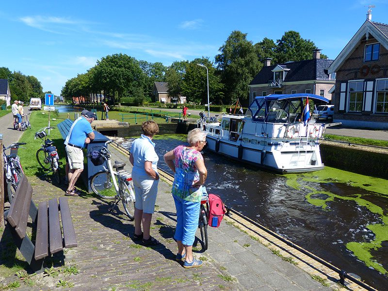 Fietsers kijken graag naar het schutten van boten die de Turfroute bevaren, zoals hier in Wijnjeterpverlaat in de gemeente Opsterland.