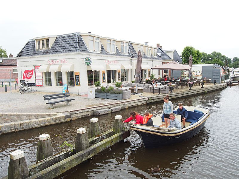 Sloepvaarders uit Earnewâld willen naar de historische binnenstad van Leeuwarden, maar stuiten op de lage ophaalbrug in Warten die twee keer midden op de dag een uur dicht is. Sommigen wachten op het terras van De Kok en de Walvis op wat gebeuren gaat: niks.