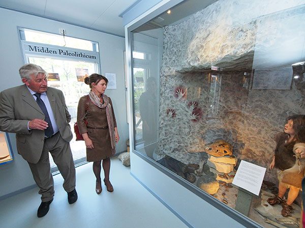Jan Kloosterman leidt gedeputeerde Jannewietske de Vries langs de vitrines over het Midden-paleolithicum in het nieuwe deel van het IJstijdenmuseum. Dit deel van de permanente expositie gaat over de Friese Wouden van 300.000 jaar geleden tot 35.000 jaar geleden, het tijdvak van de Neanderthaler.